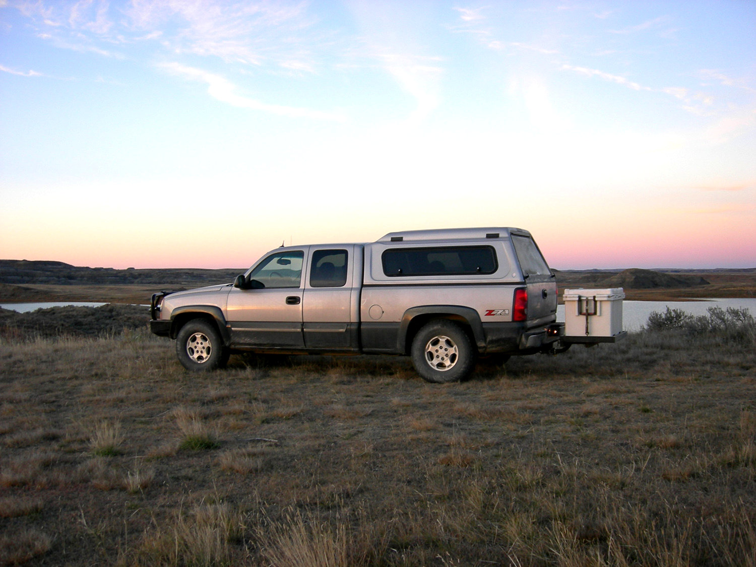 Chevy Silverado with Stowaway Hitch Frame and Platform with Pelican Cooler in a field near a pond.